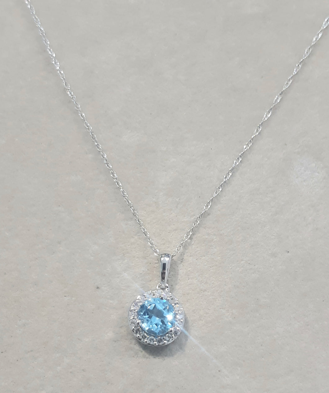 0.75ct Round Cut Blue Topaz | 0.10cts Round Brilliant Cut Diamonds | Halo Design Pendant and Chain | 14kt White Gold